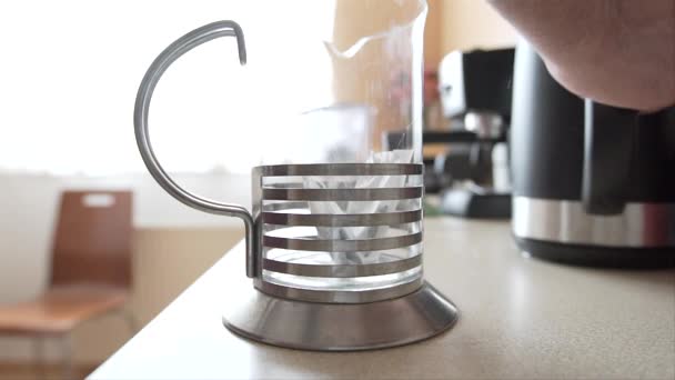 用高脚玻璃瓶泡茶 一个人把两个茶袋扔进罐子 然后倒热水 茶变色了 — 图库视频影像