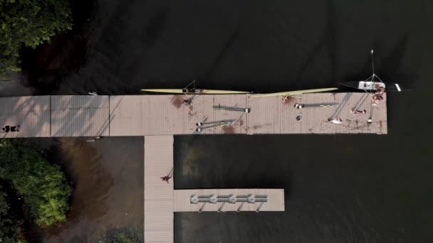 ジャネイロ市内の湖では 着陸ステージと訓練施設を見下ろす安定した空中トップダウンで ボートをフレームから収納するために水から漕ぎ手が到着して出てくる — ストック動画