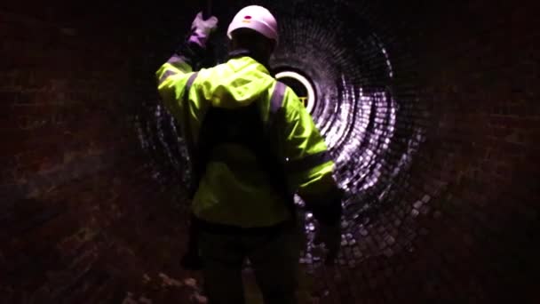 下水道地区の労働者が19世紀の古い下水道トンネルの光で道を行く — ストック動画