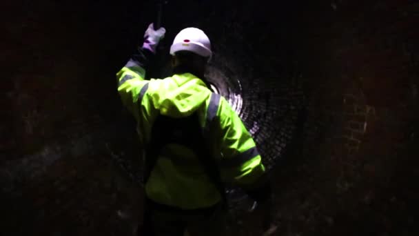 下水道地区の労働者が19世紀の古い下水道トンネルの光で道を行く — ストック動画