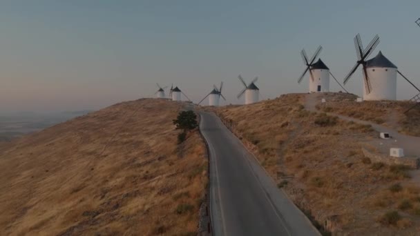 スペインのコンスエグラにある風車の列の近くの道路上で空中撮影 — ストック動画