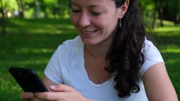 Közepes Felvétel Egy Fiatal Nőről Aki Parkban Füvön Közösségi Médiában — Stock videók