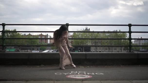 黒波状の髪と花のドレスを歩くと彼女の後ろにボートや建物のビューでロンドンで回転とファッショナブルなラティーナの観光客 — ストック動画