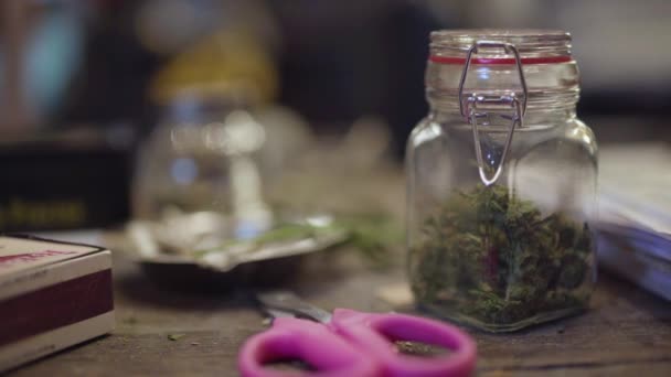 Een Potje Marihuana Een Vieze Tafel Naast Een Roze Schaar — Stockvideo