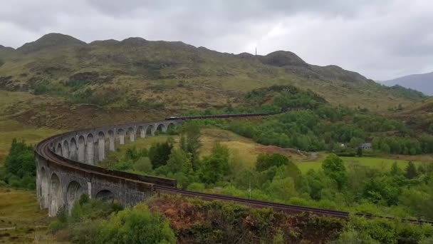 グレンフィンナン鉄道夏の雨の日にジャコバイト蒸気機関車とスコットランドのヴィアドュート ハリー ポッター映画のホグワーツ エクスプレスとしても知られるジャコバイト蒸気機関車 — ストック動画