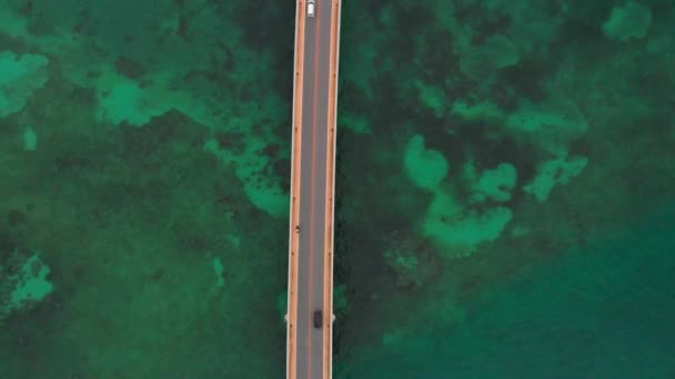 沖縄県宮古島市海に架かる橋を渡る車の空中風景 緑の海に架かる伊良部大橋 — ストック動画