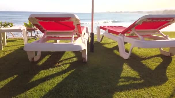 在西班牙的一个海滩上 有两张日光浴床和一张绿草阳伞 可以俯瞰大海 在西班牙马拉加的马贝拉拍摄 — 图库视频影像