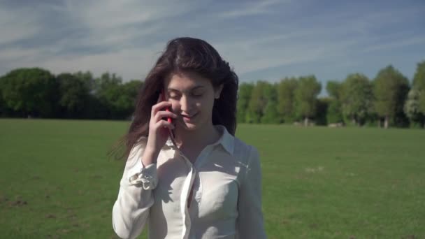 斯泰迪卡姆在公园里散步和打电话时拍摄了一个年轻美丽的意大利姑娘的照片 她的心情很好 — 图库视频影像