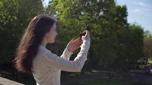 美しいイタリア人女性観光客ウィンブルドンの公園の写真を撮る 幸せな若い観光客の女性は彼女のスマートフォンで写真を撮る — ストック動画