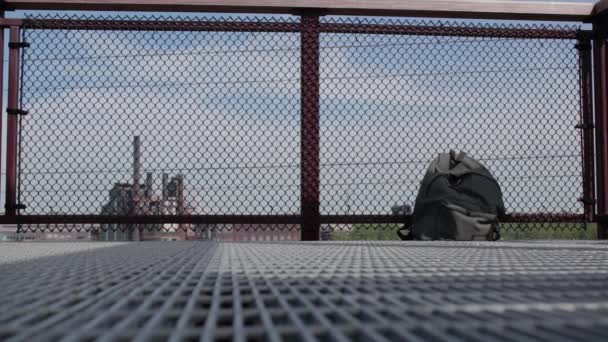 如果你看到什么 说点什么 这个孤立的背包坐落在一座桥的边缘 背景是一座工业大楼 — 图库视频影像
