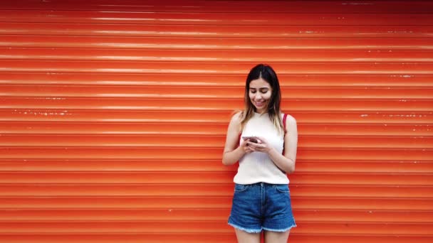 Αργή Κίνηση Όμορφο Νεαρό Κορίτσι Χρησιμοποιεί Smartphone Μπροστά Από Πορτοκαλί — Αρχείο Βίντεο
