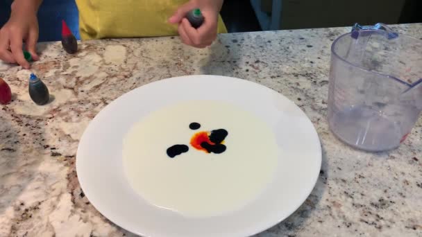 Küçük Eller Beyaz Süt Tabağına Farklı Renkte Gıda Boyası Döküyor — Stok video