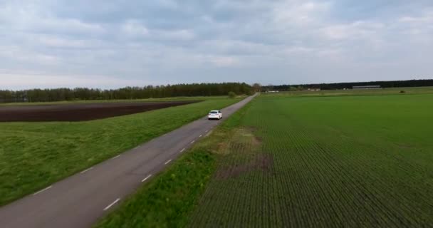 南スウェーデンの狭い田舎道を運転する白い車のショットに続く空中ドローン Skne — ストック動画
