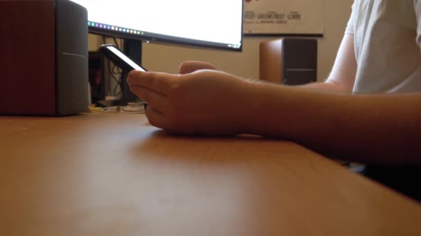 当男人坐在自家办公室的台式计算机前 他收到并检查手机上的即时通讯推送通知 — 图库视频影像