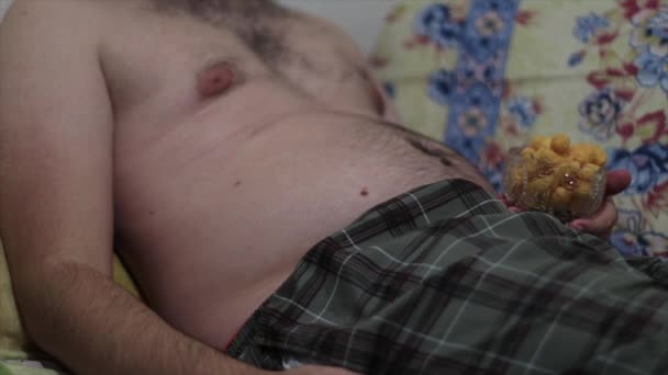 Koca Göbekli Şişman Bir Adam Kanepeye Uzanıp Tuzlu Abur Cubur — Stok video