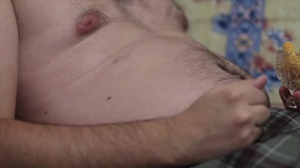 Hombre Gordo Con Gran Vientre Comiendo Bocadillos Salados Sofá Masajeando — Vídeos de Stock