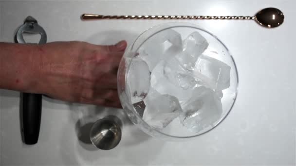 当一个男人往冰里倒入冰块和两杯蓝色烈酒来做杜松子酒和滋补品时 俯瞰着一个巨大的气球玻璃杯 — 图库视频影像