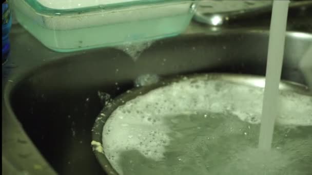 水道水の下でシンクで食器を洗うことで家庭での水使用量の過剰使用 — ストック動画