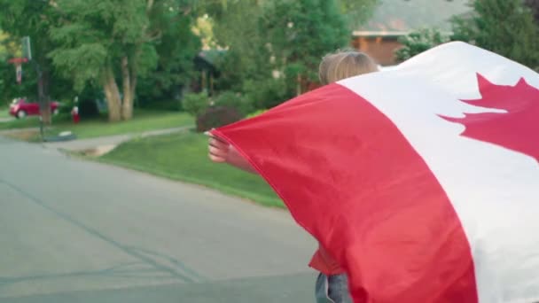 Chica Montando Longboard Por Una Calle Residencial Ondeando Bandera Canadiense — Vídeos de Stock