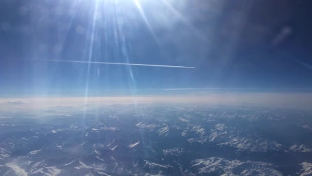 遠くを飛行する飛行機の白い歩道とヨーロッパのアルプスの上から雪の山を示す飛行機の映像 — ストック動画