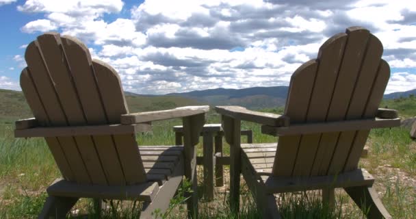 山の広大な景色を見下ろす2つの木製の芝生の椅子のショット — ストック動画