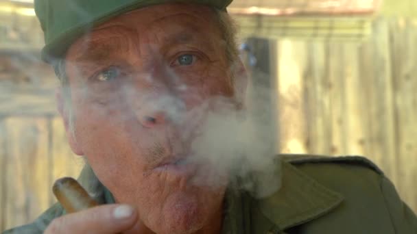 60代の青い目のハンサムな男性によってカメラで吹き飛ばされた重い煙を示すビデオ 面白いスローモーションクリップ — ストック動画