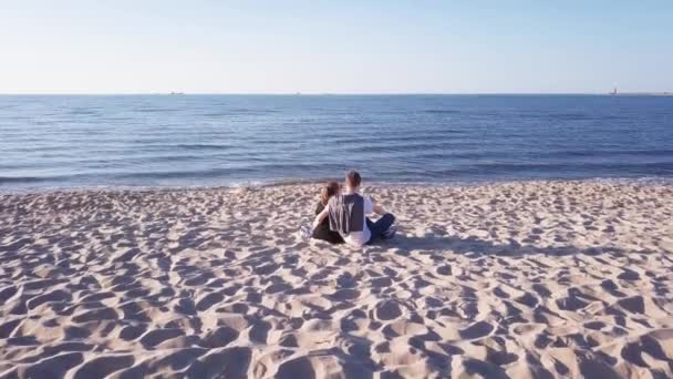 年轻情侣坐在沙滩上的空中射击 飞行员缓慢地向前和向上飞行 午后灯会 — 图库视频影像