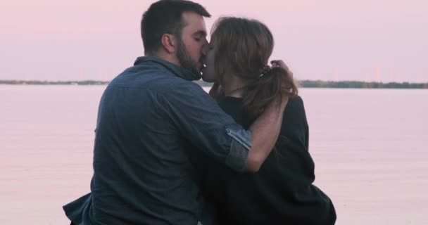 千年のカップルのスローモーションショット情熱的に日没時に湖にキス — ストック動画