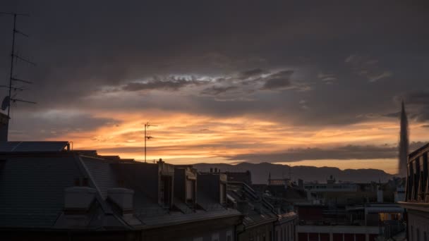 スイスのジュネーヴの屋根の上で日没の時間経過 太陽が沈むと雲や有名な噴水の色が変わります — ストック動画
