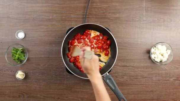 他の成分と木製のテーブルの上に大きな鍋にクリーミーなトマトソースを攪拌木製のへらのトップダウンショット — ストック動画