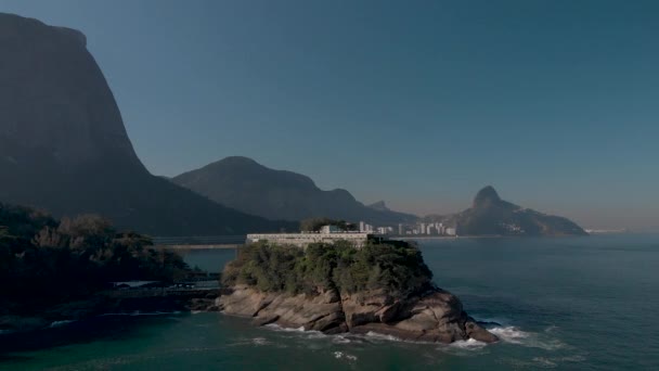 リオデジャネイロの海岸にある小さな島の空中アプローチ 晴れた日の午後には 2人の兄弟とCorcovado山の有名な都市のピークがあります — ストック動画