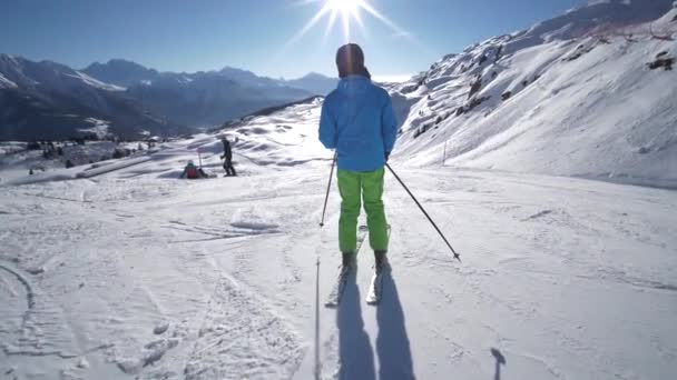 ゆっくりとした動きを追跡する 雲一つない日の間にスイスアルプスのスキーリゾートで完璧な斜面に美しい冬の日に若いスキーヤースキー — ストック動画
