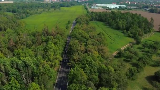 从空中俯瞰在田野和森林之间的公路上行驶的汽车 — 图库视频影像