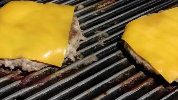 两个自制的芝士汉堡在一个黑色烤架上烹调 — 图库视频影像