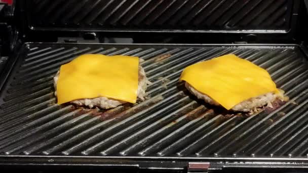 两个自制的芝士汉堡在一个黑色烤架上烹调 — 图库视频影像