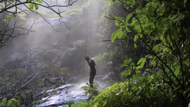 慢镜头宽拍一个快乐的非洲男人在热带瀑布下跳舞 — 图库视频影像