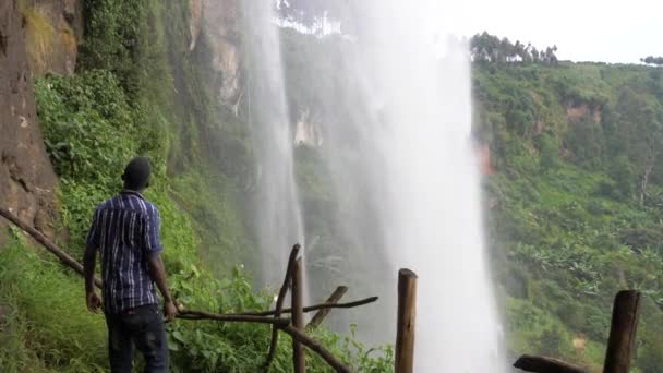 Αφρικανός Στέκεται Πίσω Από Έναν Τροπικό Καταρράκτη Κοιτώντας Ψηλά Δέος — Αρχείο Βίντεο
