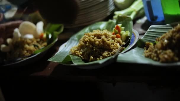 彼らのインドネシア料理を準備する通りのベンダーのショット 食事はバナナの木の葉で提供されるチャーハン ナシゴレン — ストック動画