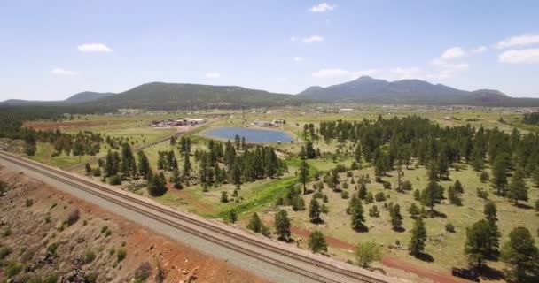 空中拉回平行的铁路轨道上 可以看到亚利桑那州威廉姆斯附近的土路 池塘松和小湖泊 美国西南部 — 图库视频影像
