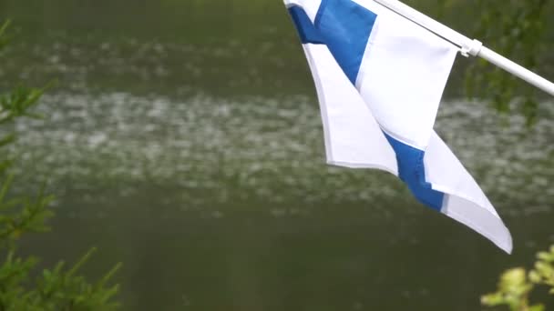 芬兰的国旗在湖边的乡村小屋迎风飘扬 缓慢地倾斜着 — 图库视频影像