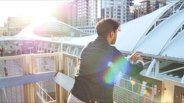 Ein Junger Mann Jeansjacke Blickt Über Einen Balkon Der Stadt — Stockvideo