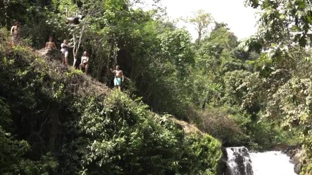 在印度尼西亚巴厘岛的Alingaling瀑布 一名游客跳下悬崖 拍摄了慢镜头 那个跳起来的人从悬崖上跳到了水里 — 图库视频影像