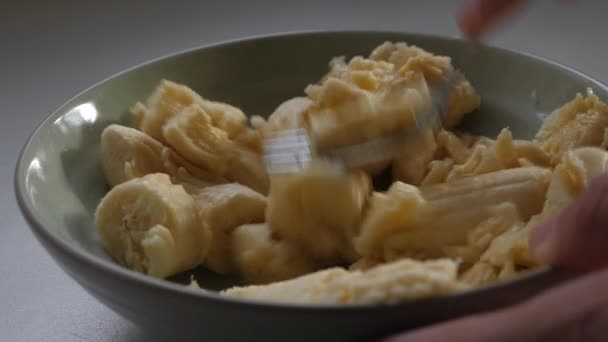 人们在小碗里把切碎的香蕉捣碎 小碗上有金属叉子 — 图库视频影像