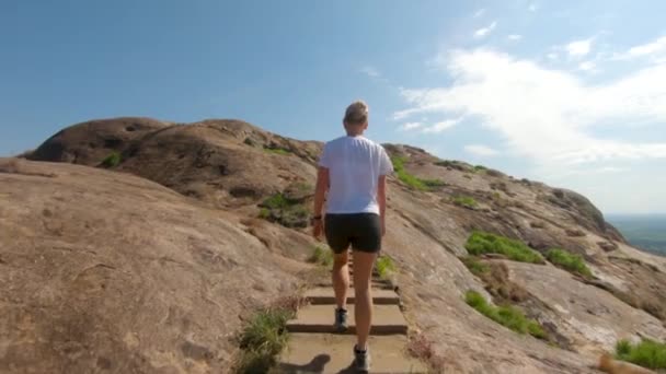 동아프리카에 화강암 산에서 계단을 오르는 금발의 부인의 뒤에서 동작으로 — 비디오