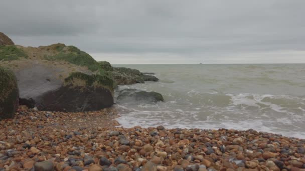 在云天里 英国一个鹅卵石海滩的低射 海浪在照相机附近冲破 — 图库视频影像