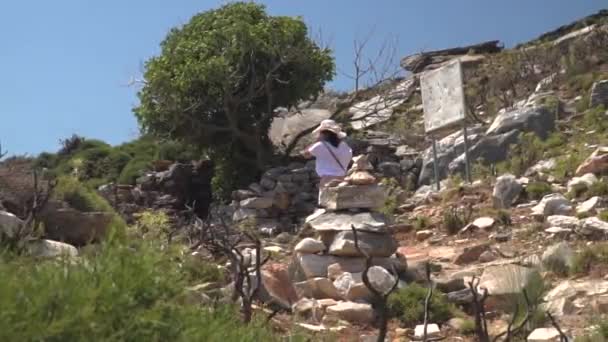 从右到右穿行在到达的女孩 干燥的风景与石头 枯树和一些植被 — 图库视频影像