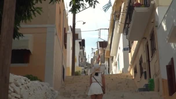 女の子から上へ夏のドレスでギリシャの旗までのステップアップで狭い路地でシロス — ストック動画