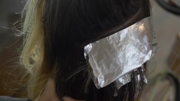 女性のヘアスタイリストは クライアントの髪に箔を折る — ストック動画