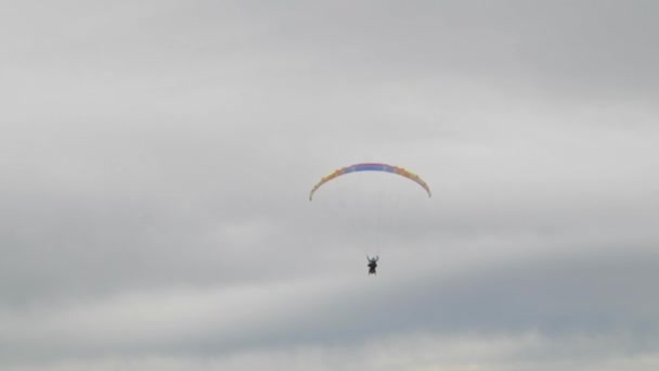 曇りの日に遠くを飛ぶパラグライダーの写真です — ストック動画