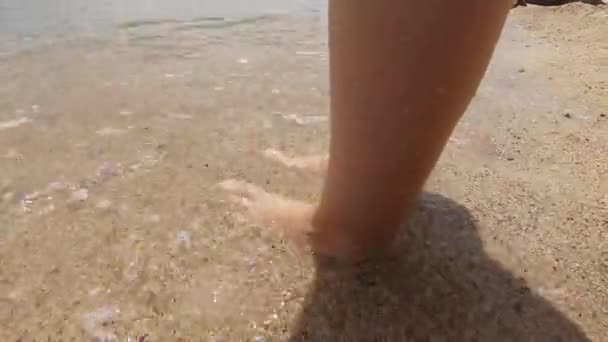 一个女人站在沙滩上的海边 海浪缓缓地拍打着她的脚 一个平静祥和的氛围 一个美妙的暑假 — 图库视频影像